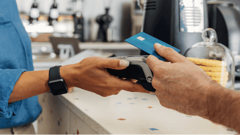 Cliente realizando un pago sin contacto en un terminal POS, ilustrando laoptimización del procesamiento de tarjetas de débito y crédito