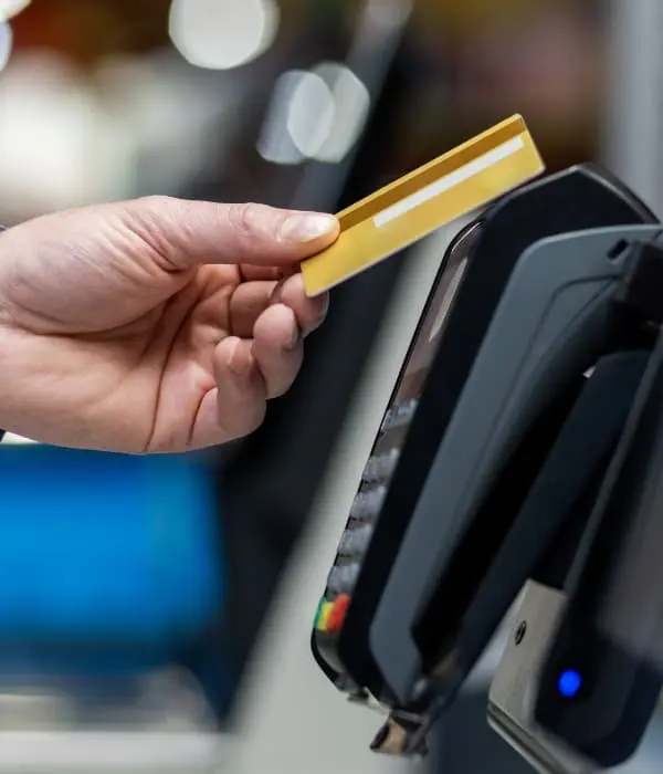 Cardholder making a contactless payment with a credit card at a POS terminal, illustrating card processing optimization.