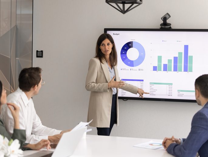 A team reviewing budget charts on a screen in a meeting room