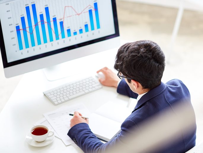 An analyst reviewing scheme fee data on a monitor